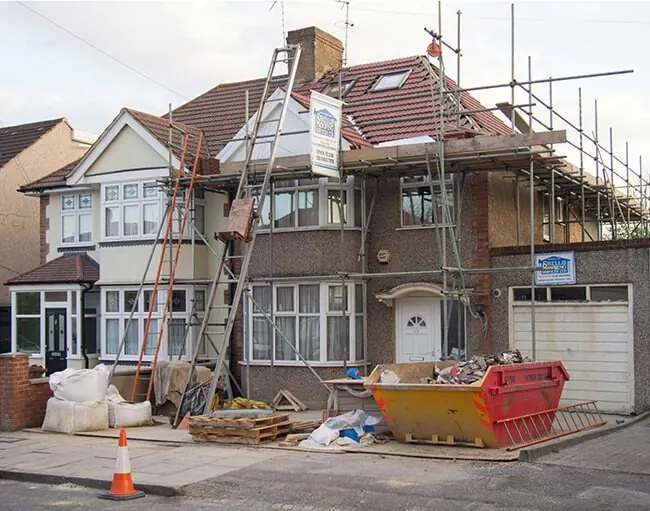 Two-story home remodel with scaffolding and a dumpster