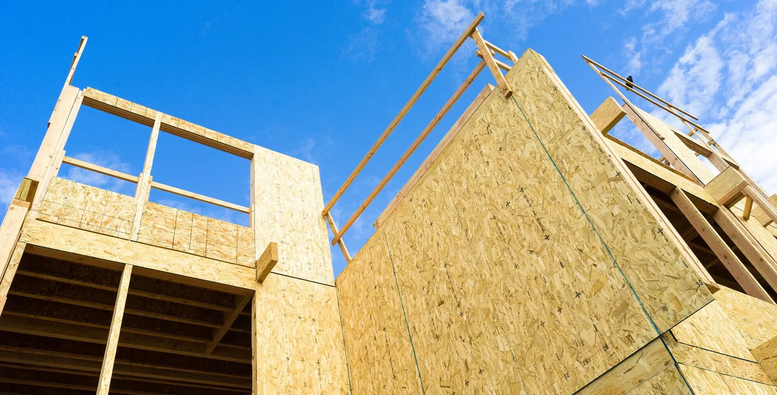 New home framing with OSB sheathing against a blue sky